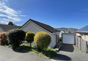 A residential house with a garage, neatly trimmed hedges, and a clear sky. - Skiddaw Heights - sleeps 4 guests  in 2 bedrooms (Central Keswick)