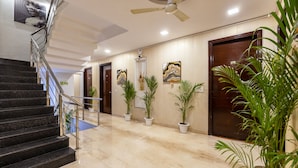 A hotel lobby with marble flooring, a staircase with metal railings, and several potted plants. - Aliste millennium City centre, Fortis, Gurugram (Gurugram)