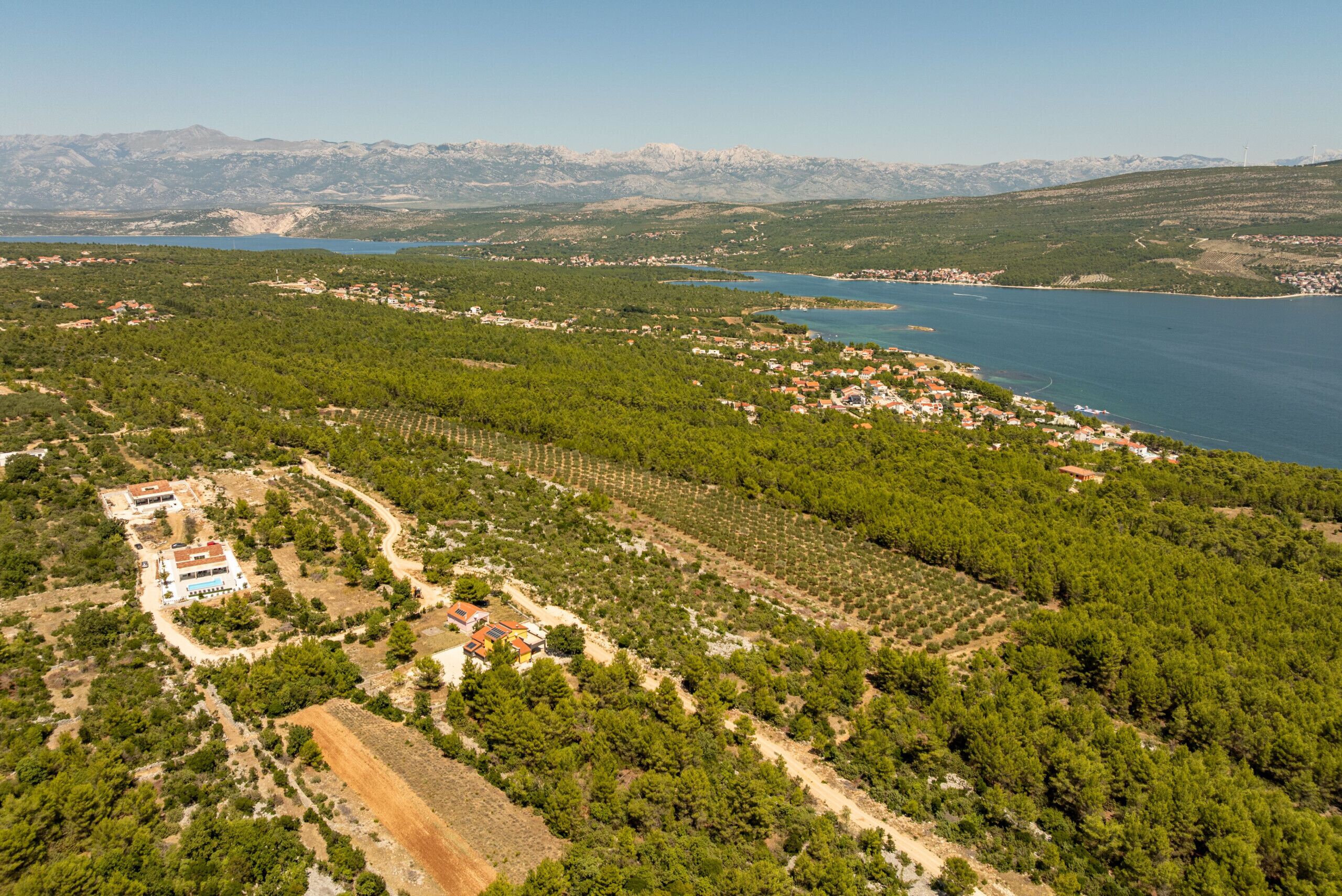 Una vista aerea di una zona costiera con un vigneto, un piccolo borgo e un lago.