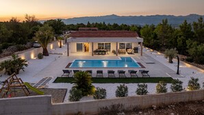 Une maison moderne dotée d’une piscine, d’un espace salon extérieur et offrant une vue sur les montagnes.