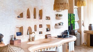 Une cuisine moderne dotée d’un grand îlot central, de murs en pierre et de divers appareils de cuisine.