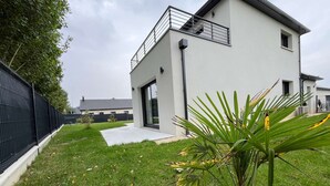 A modern two-story house with a balcony, a paved driveway, and a well-maintained lawn. - "Villa LOM: 800m from the beach (Asnelles)