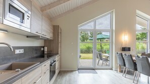 A modern kitchen with a built-in microwave, stainless steel sink, and wooden cabinets.