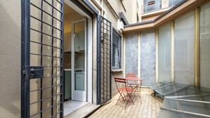 A small outdoor patio with a table and chairs, a sliding glass door, and a metal gate.