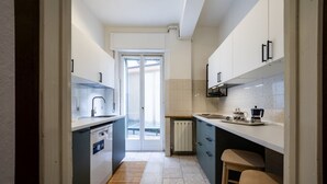 A narrow kitchen with a dishwasher, a sink, and a coffee maker on the countertop.