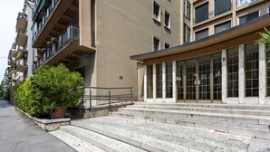 A building with a set of stone steps leading to a glass entrance, surrounded by other buildings.