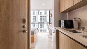 A modern kitchen with wooden cabinets, a stainless steel sink, and a black refrigerator.