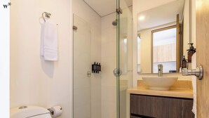 A modern bathroom with a glass-enclosed shower, a toilet, a sink with a wooden vanity, and a mirror above the sink.