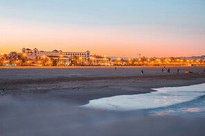 A beachfront hotel with a row of illuminated windows, a sandy beach, and a calm sea. - Travel Habitat Playa del Cabanyal 1 (Valencia)
