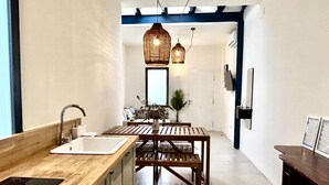 A modern kitchen with a wooden countertop, a sink, and a dining area with a table and chairs.