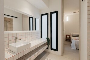 A modern bathroom with a large white sink, a mirror, and black-framed windows. - Travel Habitat Playa del Cabanyal 1 (Valencia)