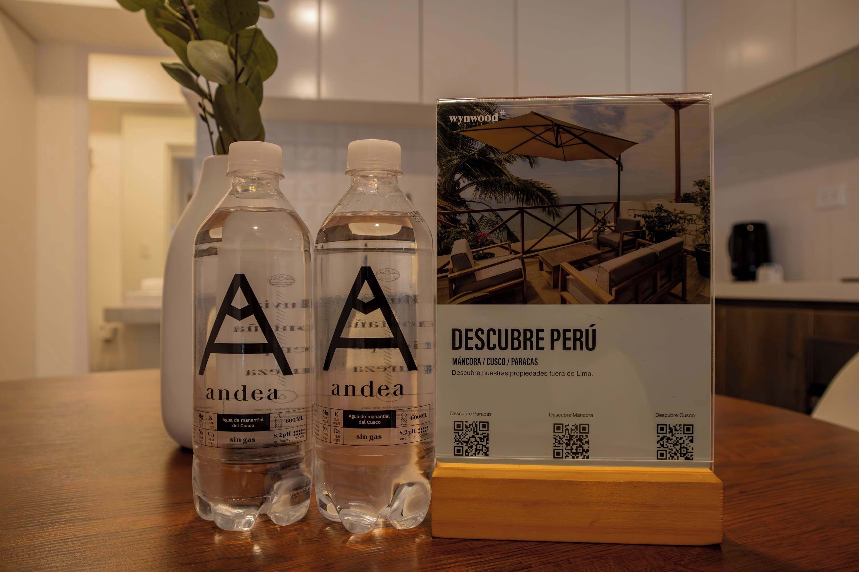 Two bottles of 'andea' water and a QR code stand with a photo of a terrace.