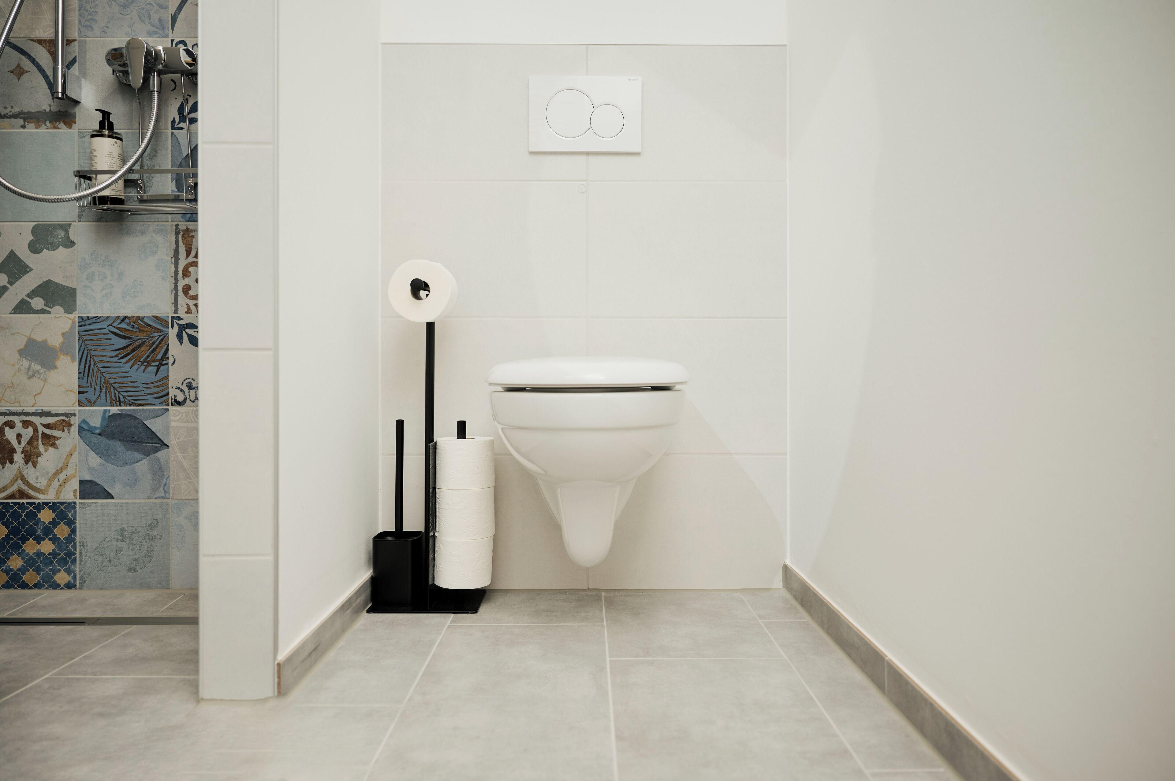 Une salle de bain moderne équipée de toilettes, d’une douche et d’un porte-rouleau de papier toilette.