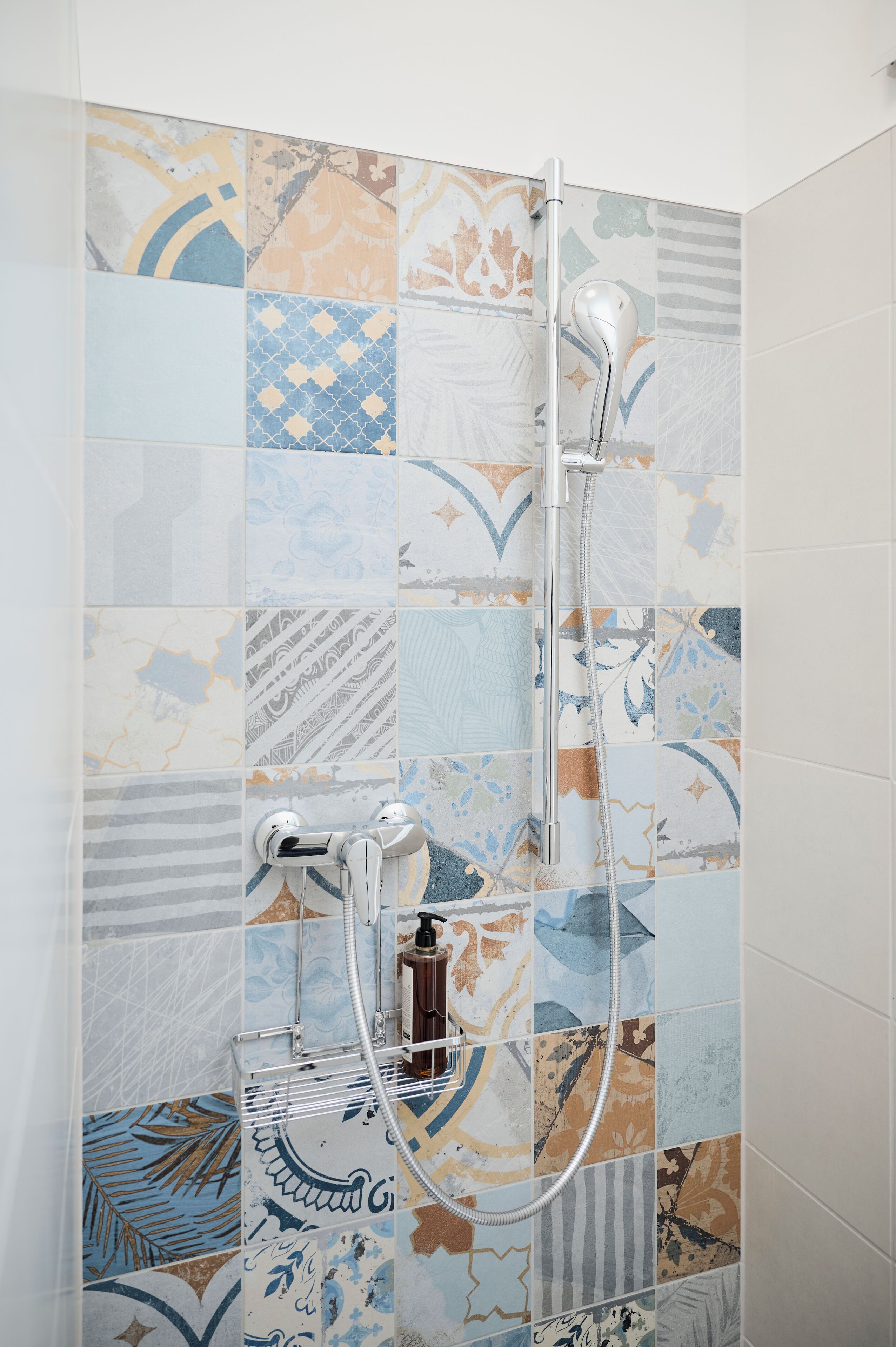 Eine Dusche mit Handbrause und Armatur an der Wand.