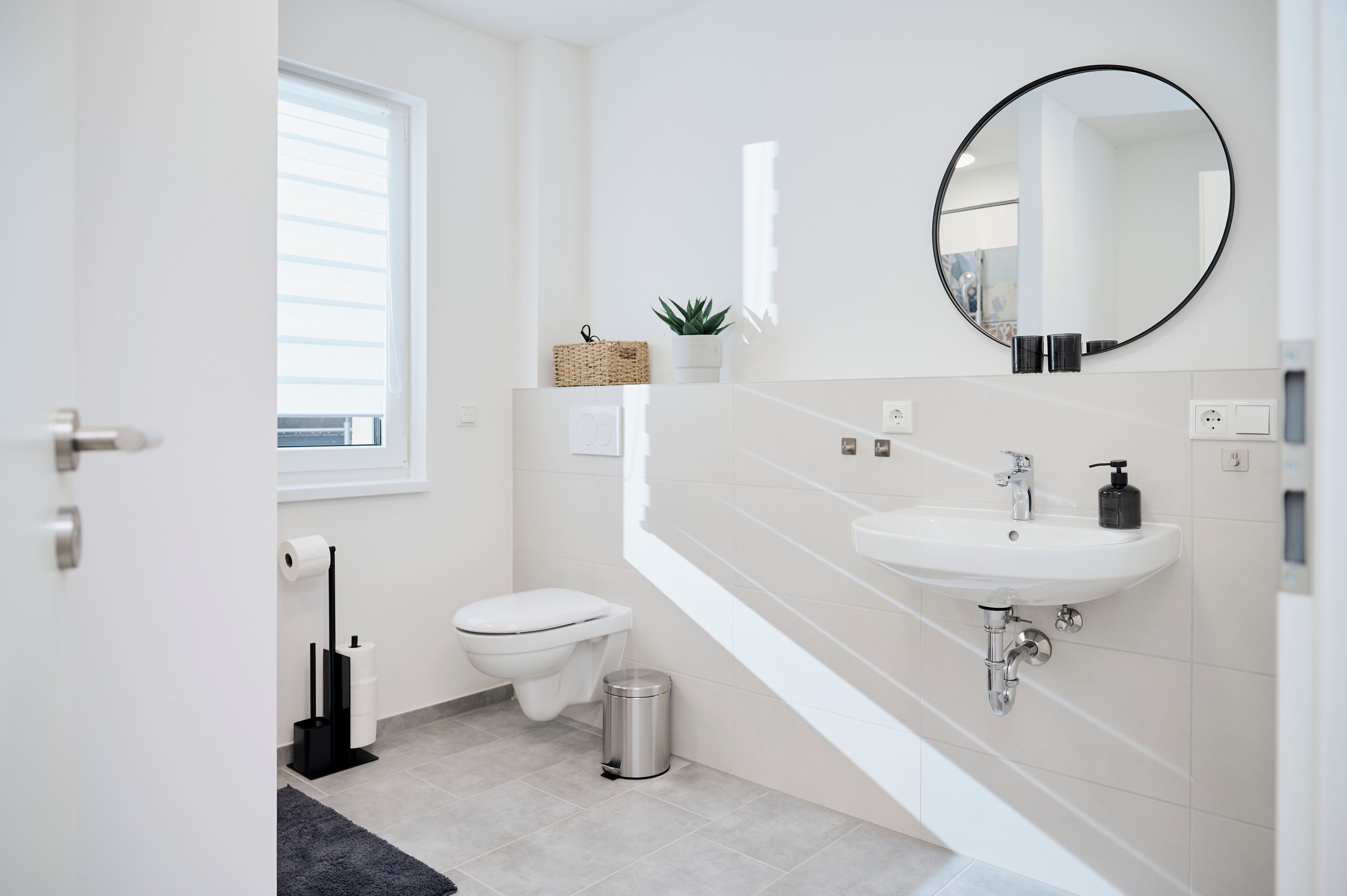 Un baño moderno con inodoro, lavamanos y espejo.