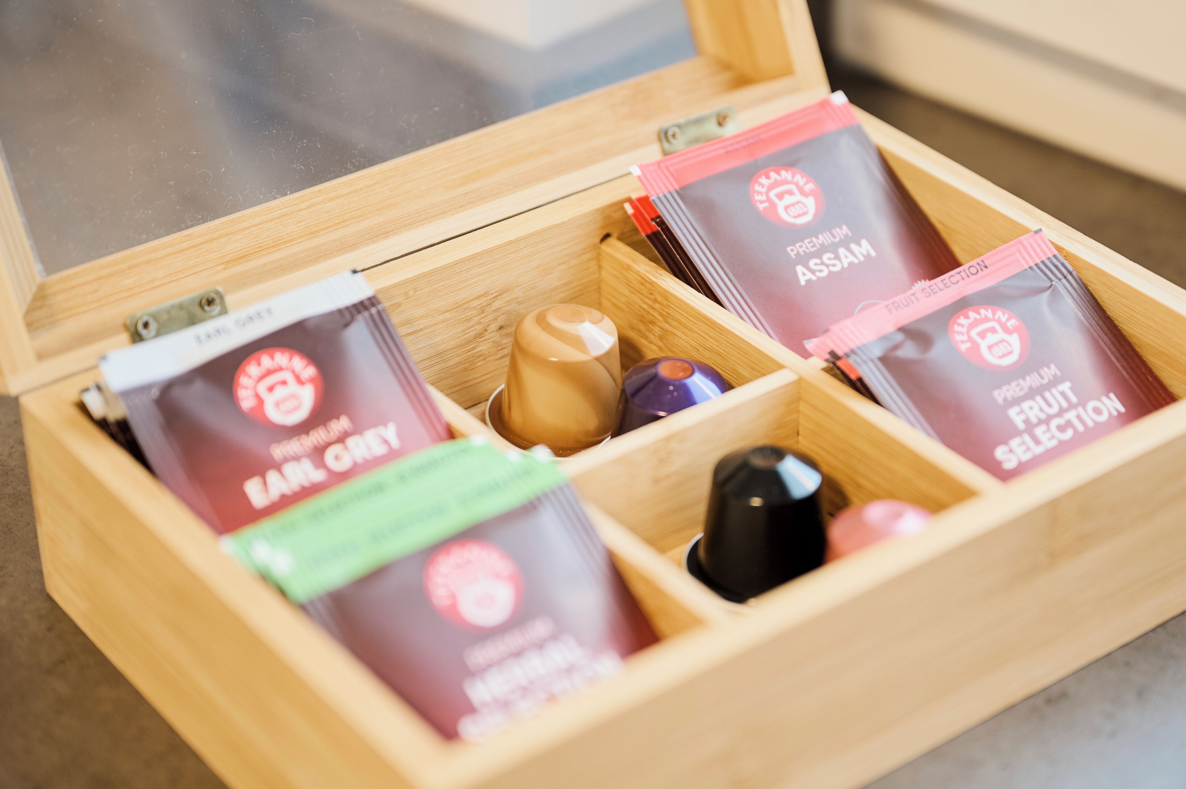 A wooden box containing premium tea bags labeled 'Earl Grey' and 'Fruit Selection'.
