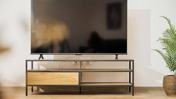 Un soggiorno moderno con una televisione a schermo piatto su un mobile in legno, una pianta in vaso e un'arredamento minimalista.