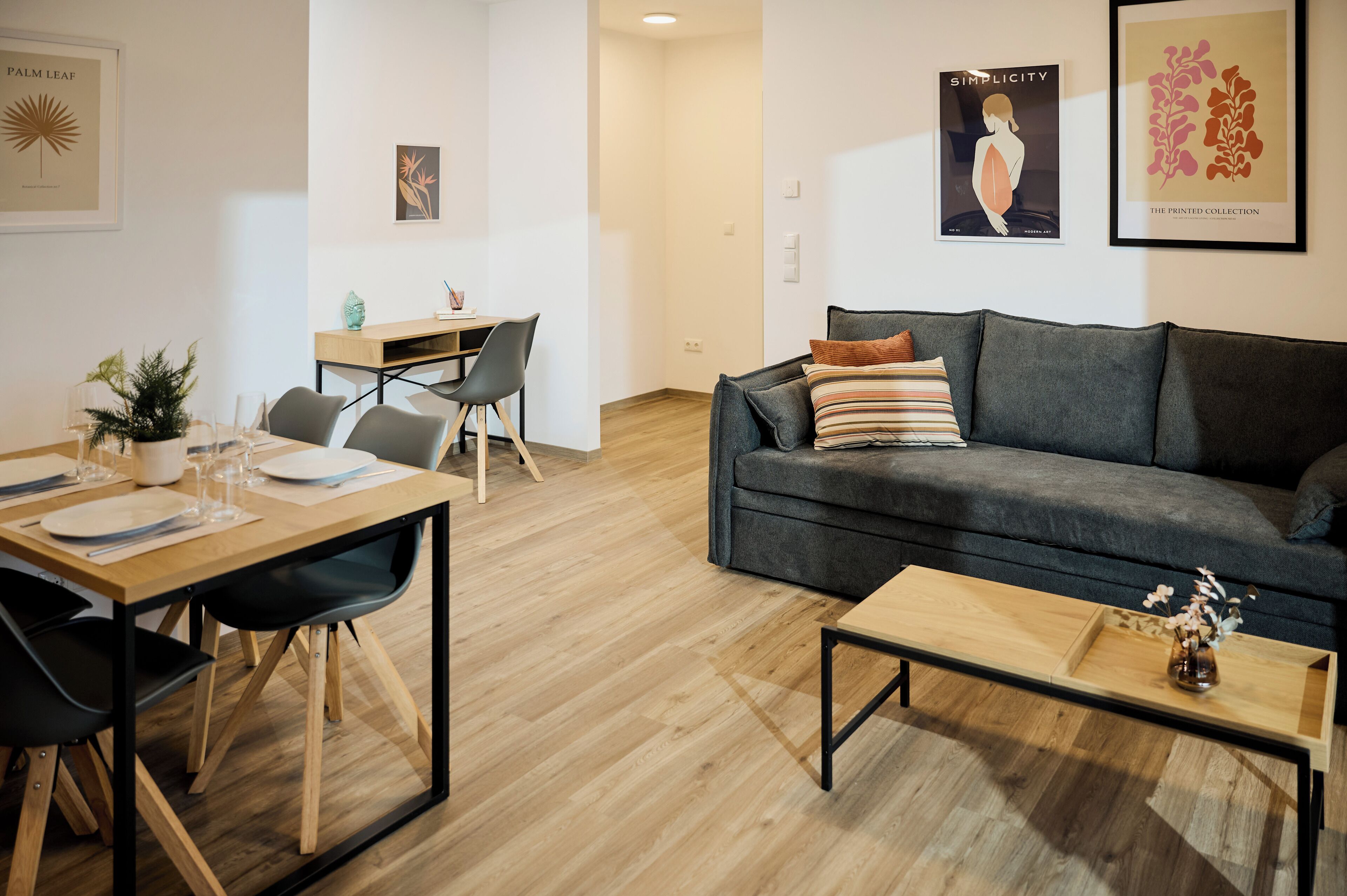 A modern living room with a dining area, a grey sofa, and a coffee table.