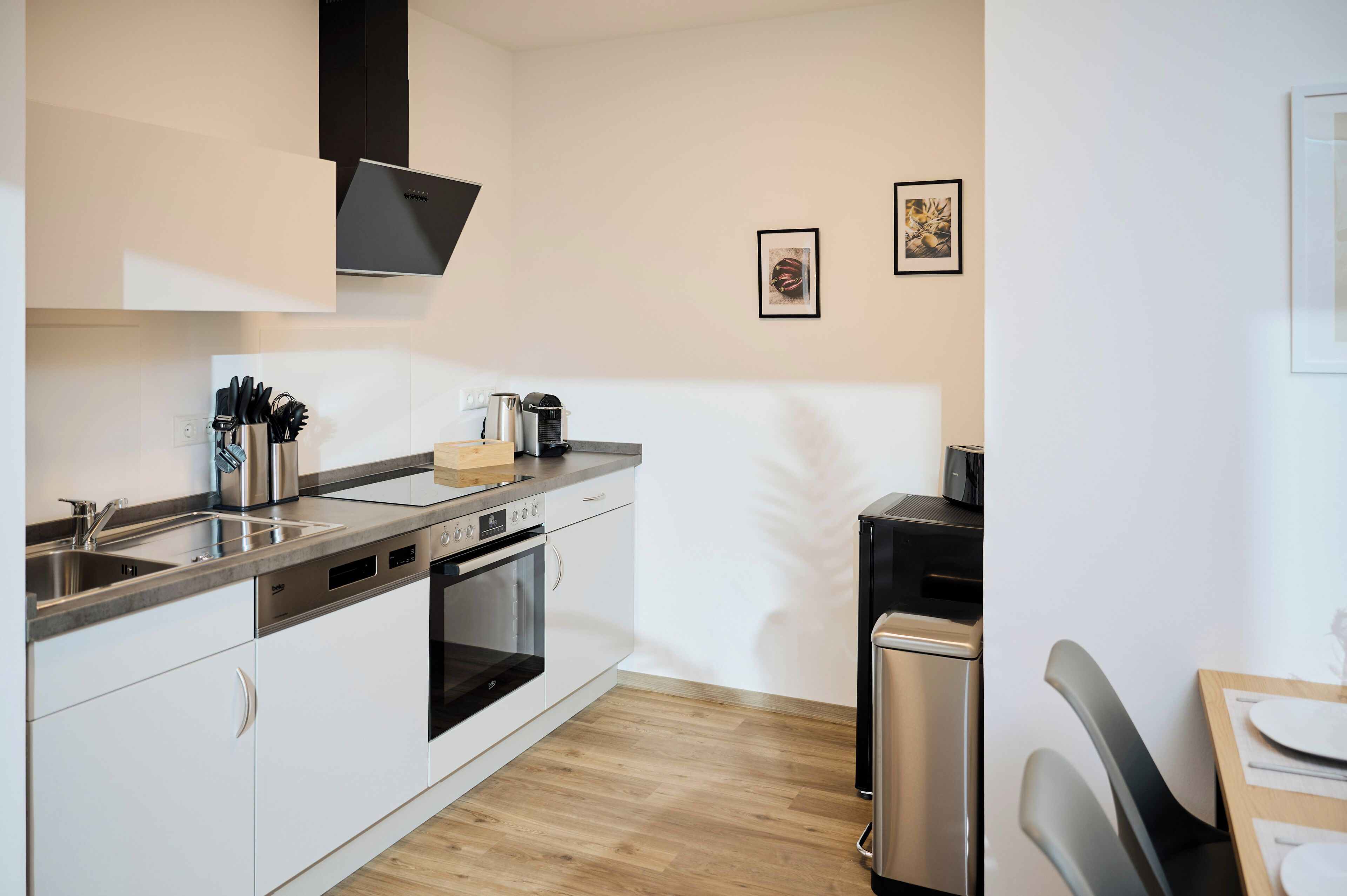 Una cocina moderna con electrodomésticos de acero inoxidable, muebles blancos y suelo de madera.