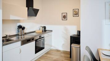 Una cocina moderna con electrodomésticos de acero inoxidable, muebles blancos y suelo de madera.