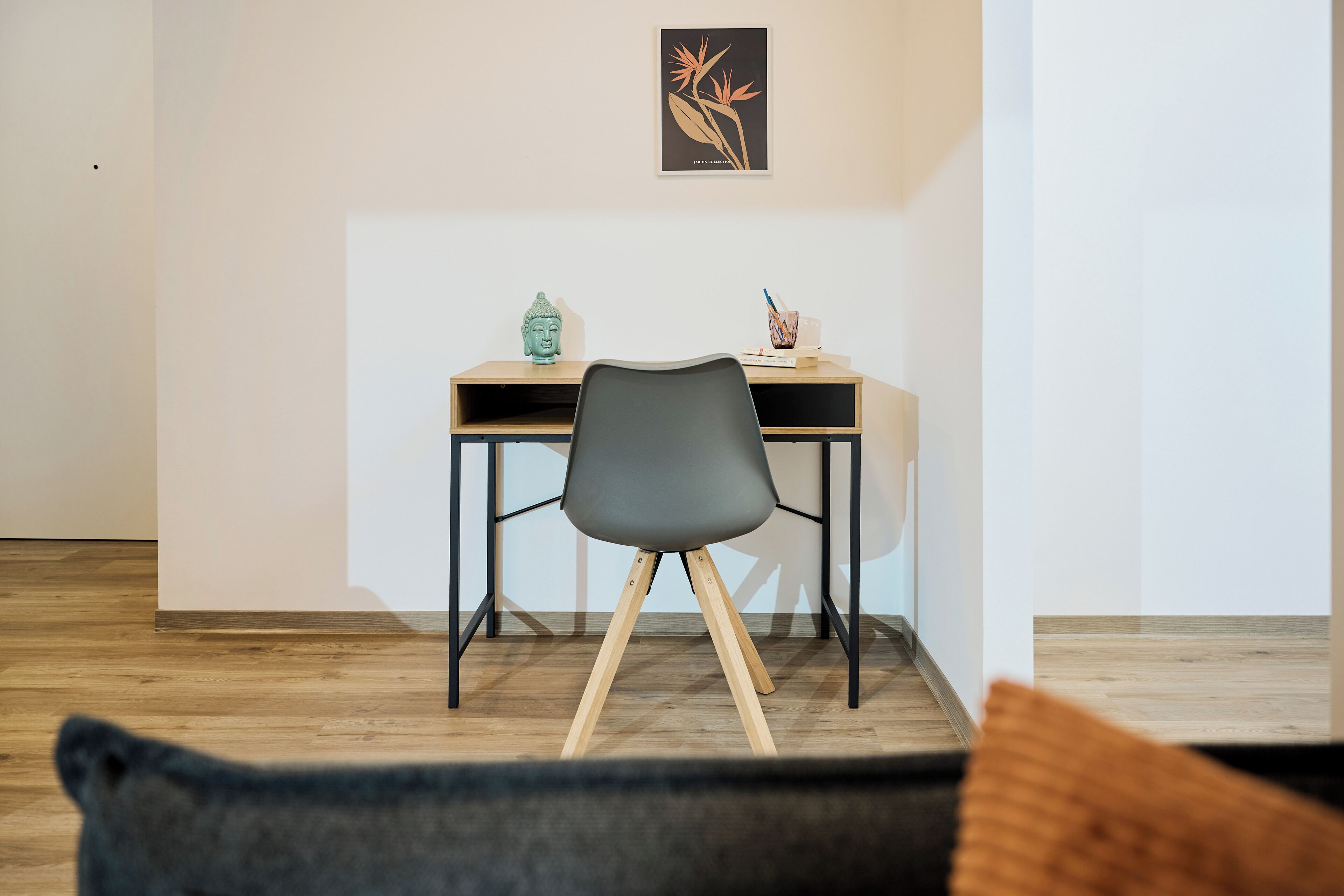 A modern room with a desk, chair, and a framed artwork on the wall.