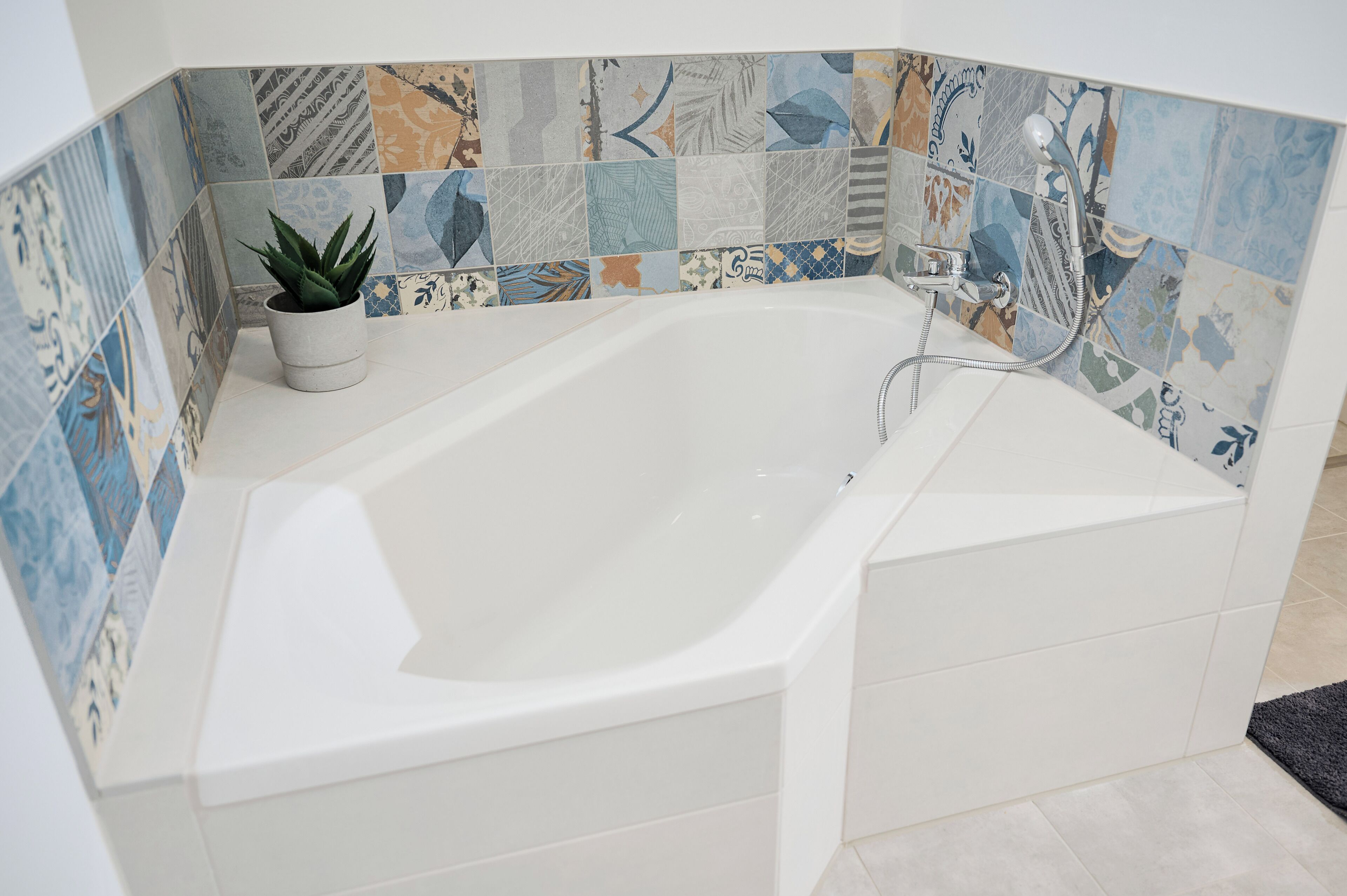 Un baño moderno con una bañera independiente, ducha y una planta en maceta.