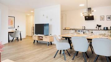 A modern kitchen with a dining area, wooden flooring, and contemporary furniture.