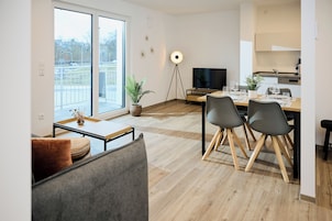 Una sala de estar moderna con un sofá, una mesa de comedor con sillas, un televisor y una lámpara de pie.