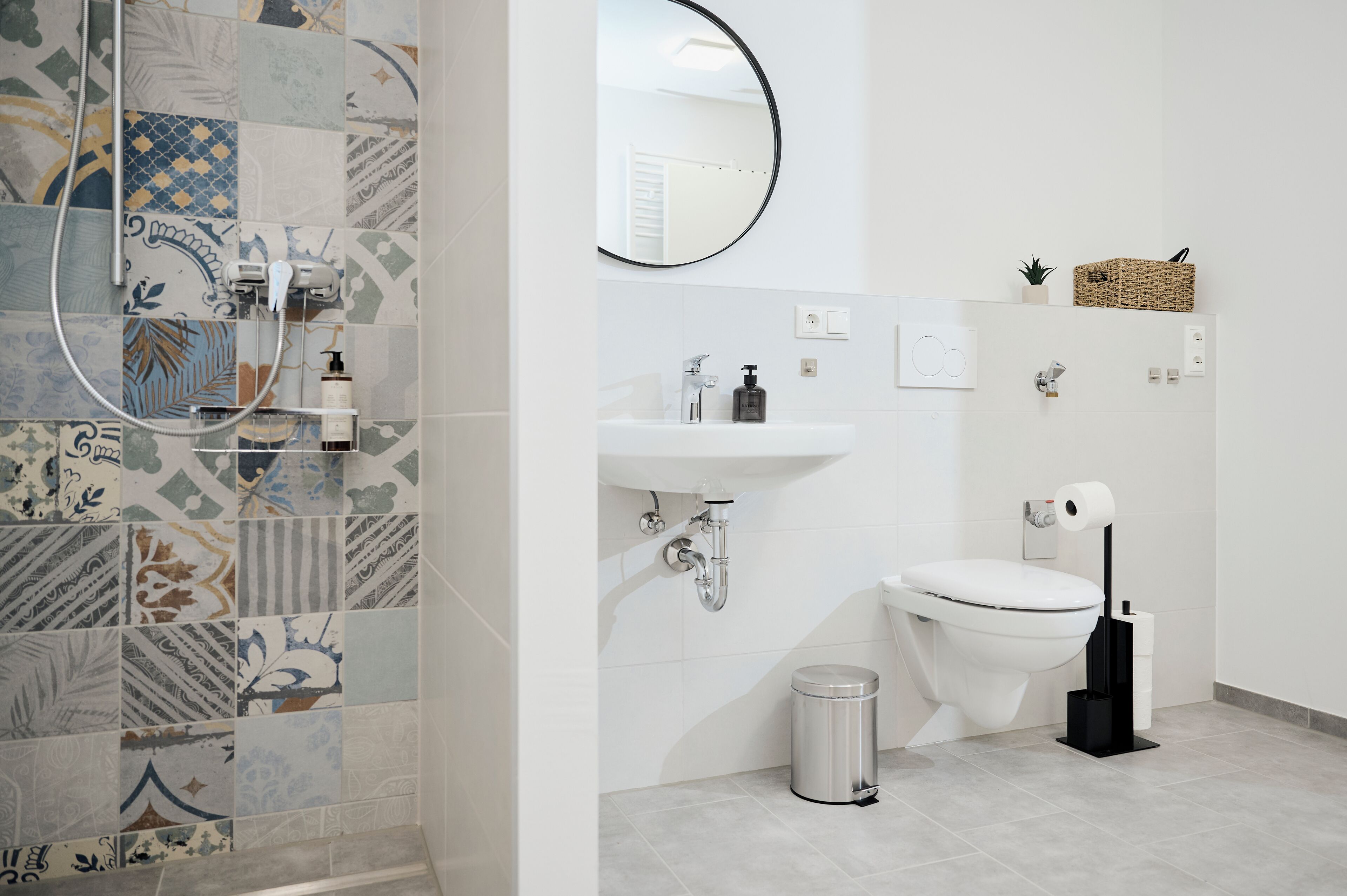 Un baño con ducha, lavamanos, inodoro y un cubo de basura.