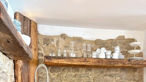 Una cocina moderna con salpicadero de piedra, estantes de madera y un lavamanos de acero inoxidable.
