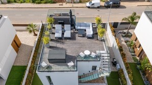 A modern rooftop terrace with outdoor seating, a glass balustrade, and a staircase leading to the upper level. - Villa Memorias | Modern | 3 Bedrooms | Albufeira (Albufeira)