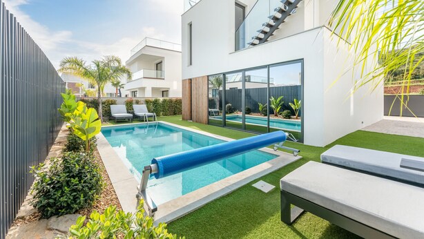 A modern outdoor pool area with a blue slide, lounge chairs, and a staircase leading to a second floor. - Villa Memorias | Modern | 3 Bedrooms | Albufeira (Albufeira)