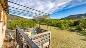 A wooden deck with a glass enclosure, a chair, and a table.