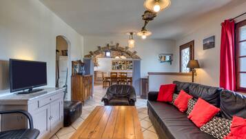Ein Wohnzimmer mit Holztisch, Ledersofa und Fernseher.