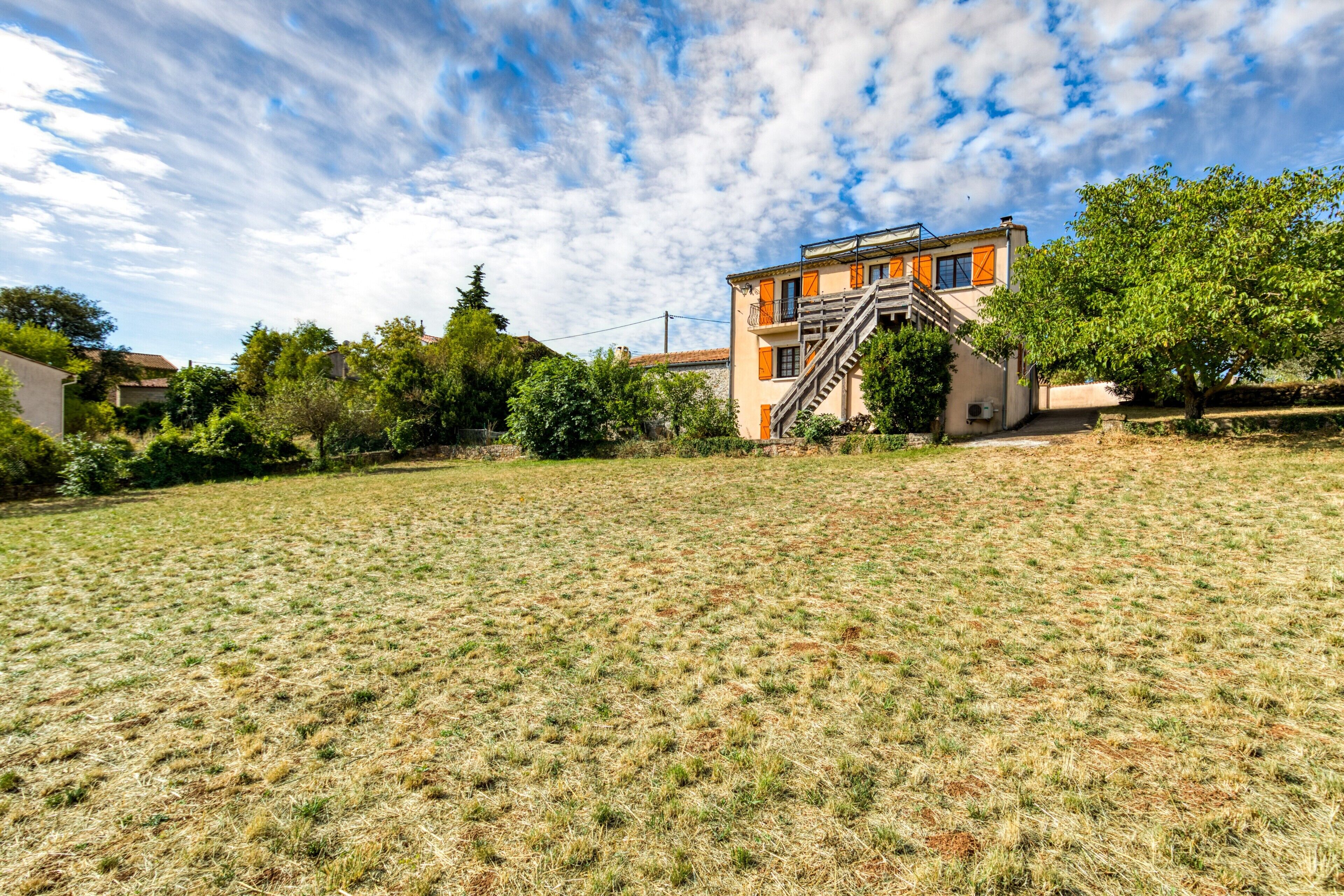 A building with a staircase, surrounded by a grassy field and trees.