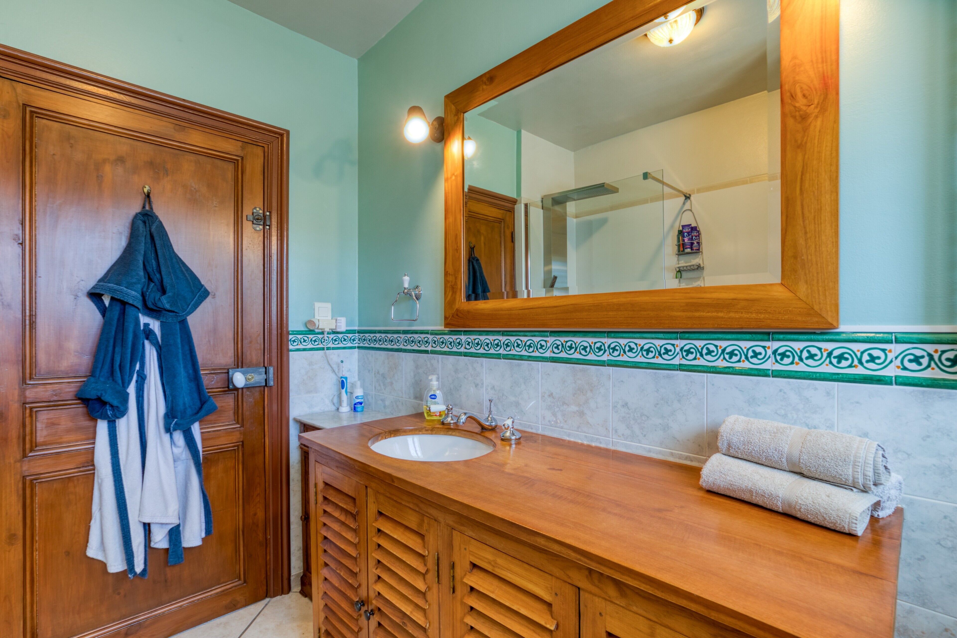 A bathroom with a wooden vanity, a large mirror, and a towel rack.
