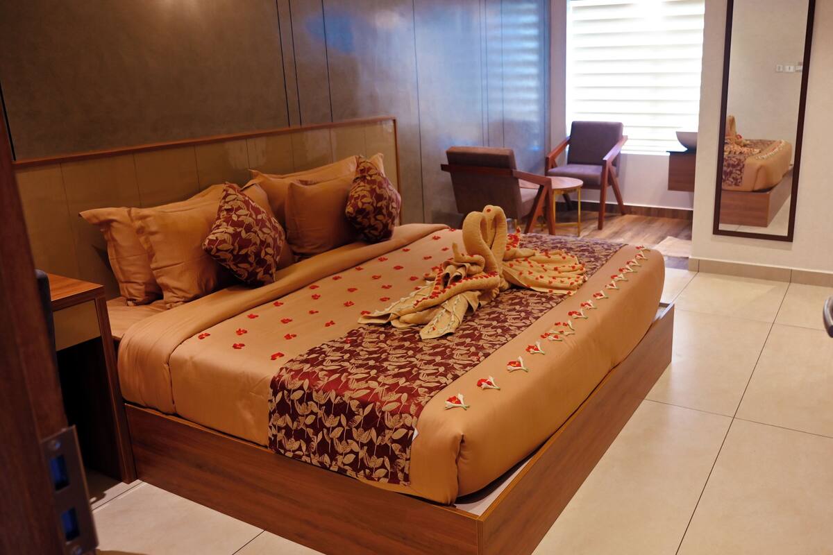 Una cama bien hecha con una colcha estampada con motivos florales, un cabecero de madera y una mesita de noche.