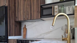 Eine moderne Küche mit Marmorarbeitsplatte, goldenem Wasserhahn und Holzschränken.