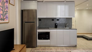 A modern kitchen with a stainless steel refrigerator, a built-in oven, and a coffee maker on the countertop. - Hazel Spaces DownTown (Cairo)