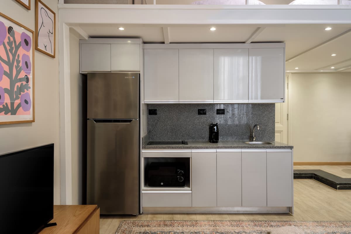 A modern kitchen with a stainless steel refrigerator, a built-in oven, and a coffee maker on the countertop.
