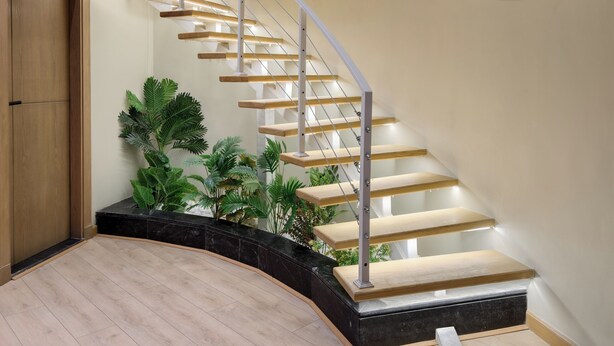 A modern staircase with a wooden finish and glass railings, surrounded by various framed artworks on the walls. - Hazel Spaces DownTown (Cairo)