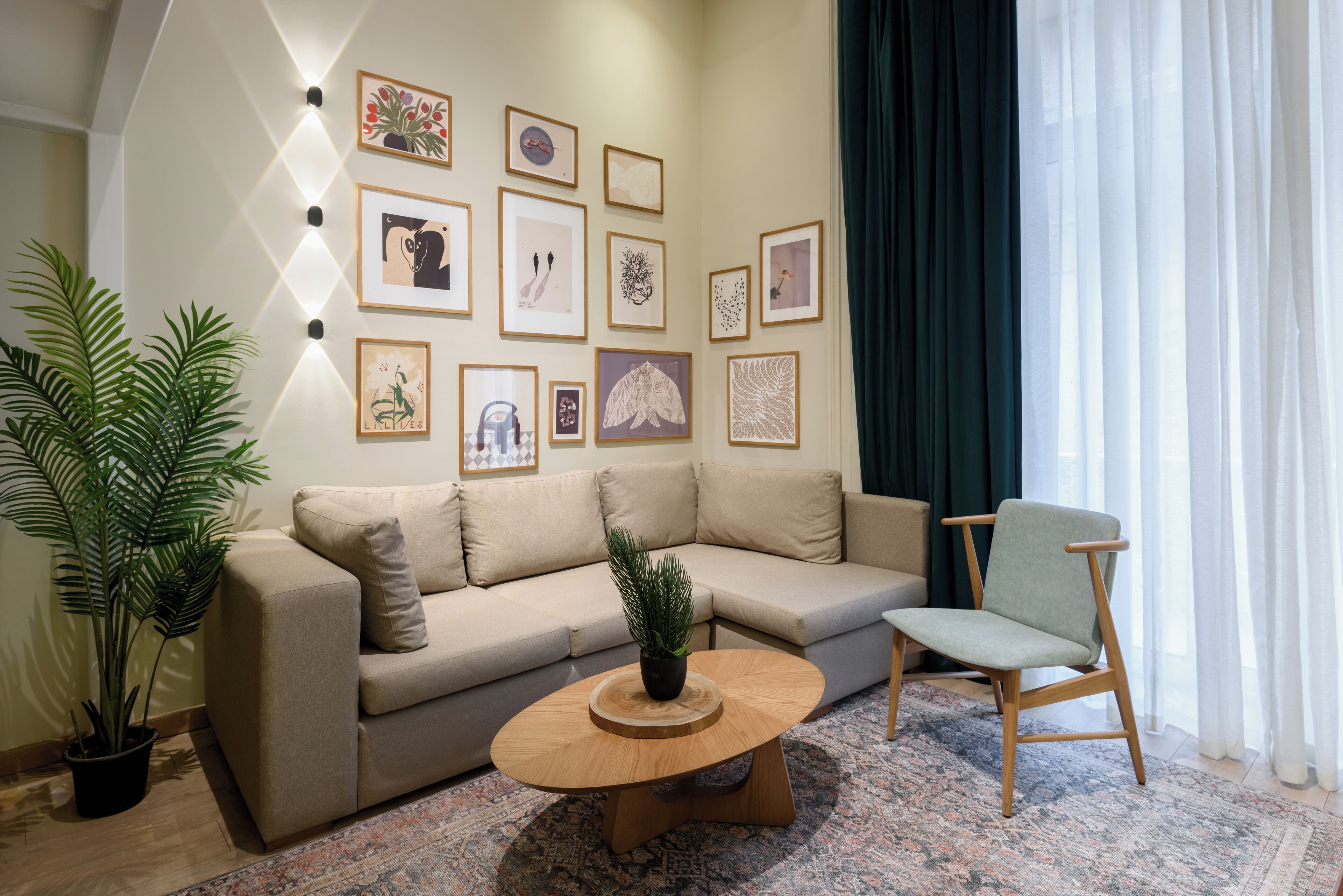 A living room with a beige sofa, a wooden coffee table, a green chair, and a large potted plant.