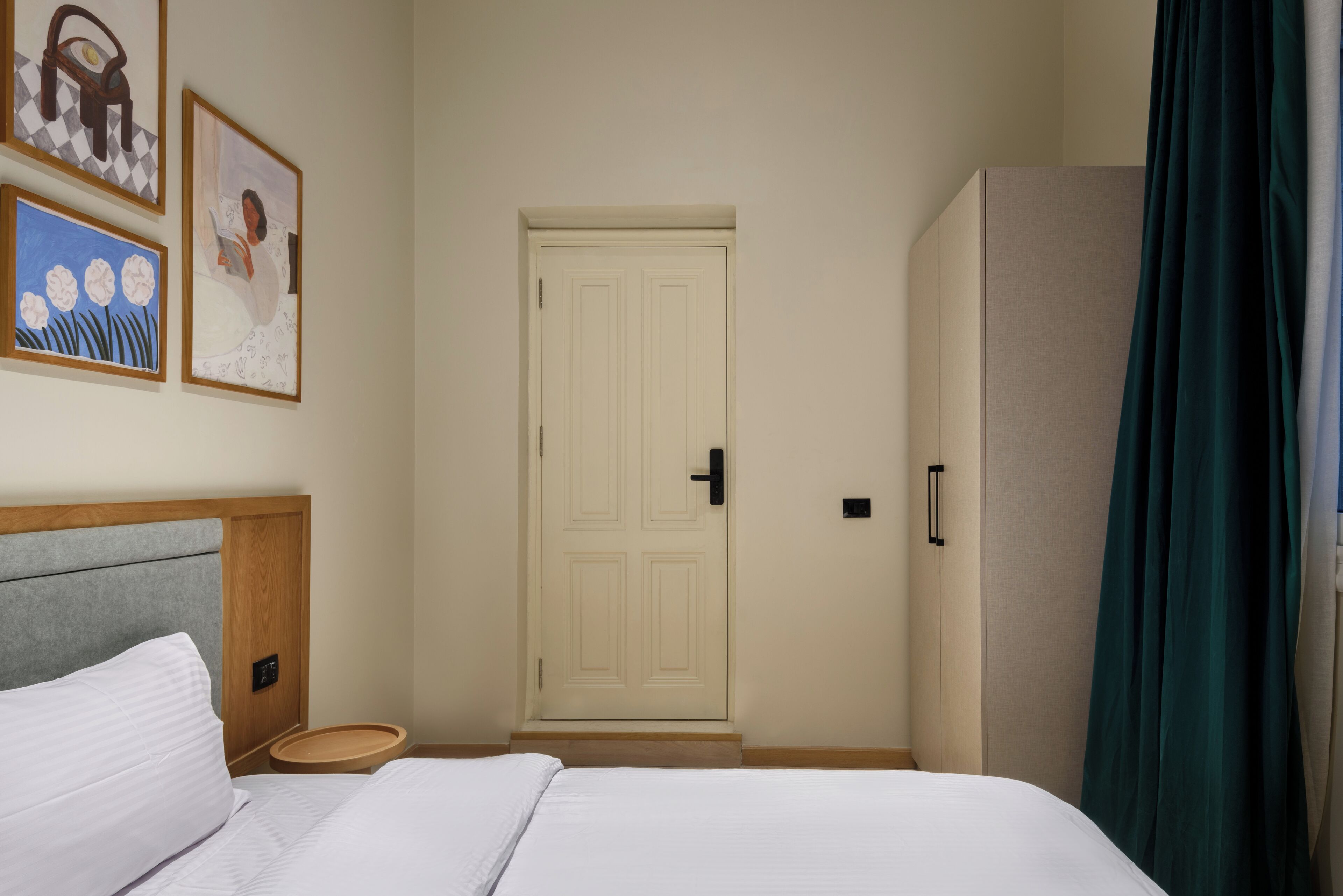 A hotel room with a bed, a door, and a wardrobe.