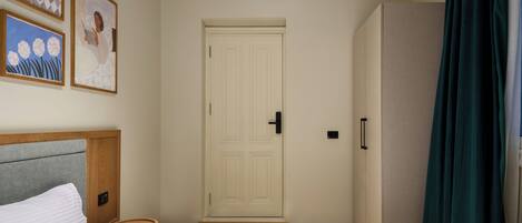 A hotel room with a bed, a door, and a wardrobe.