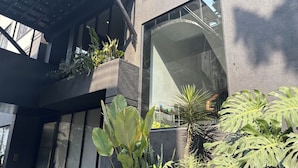 A modern building with large windows, potted plants, and a metal railing. - Wellesley Hotel (Pune)