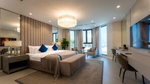 Quarto de hotel moderno com uma cama grande, uma escrivaninha e uma televisão.