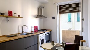A modern kitchen with a built-in washing machine, a stove, and a dining area with a table and chairs. - Corso Sardegna Design Apartment by Wonderful Italy (Genoa)