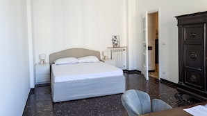 A bedroom with a bed, bedside tables, a chair, and a dresser. - Corso Sardegna Design Apartment by Wonderful Italy (Genoa)