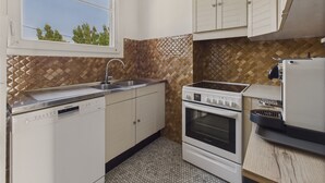 A kitchen with a window, white cabinets, a Bosch dishwasher, a Siemens oven, and a coffee machine.