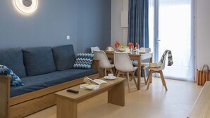 A modern living room with a sofa, coffee table, and dining area. - Résidence Odalys Référence Les Bains by Interhome (Trégastel)